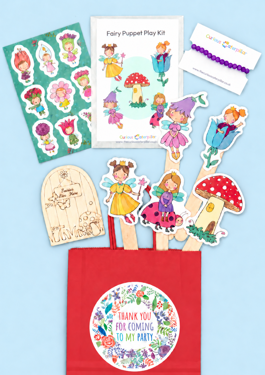 Fairy party bag with red paper bag, fairy puppet craft set, wooden fairy door, flower fairy stickers and glass bead bracelet on a light blue background; optional packaging shown